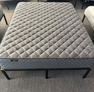 A clean, gray mattress on a black metal bed frame in a room.