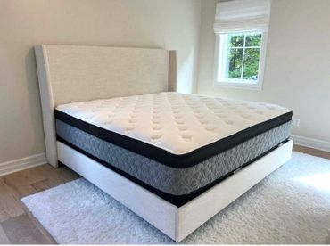 Modern upholstered bed with a plush mattress in a bright, minimal bedroom.