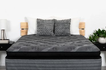 Modern bed with gray mattress and decorative pillows in a minimalist room.