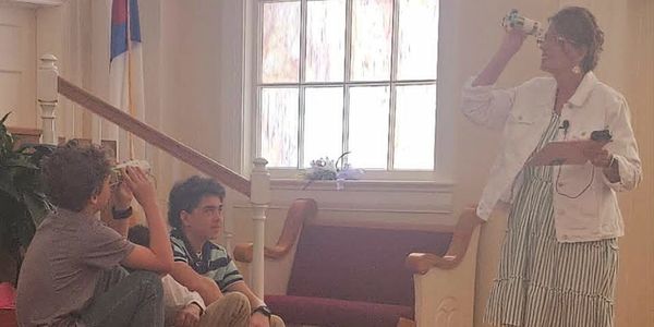 Woman and children looking through homemade binoculars inside a church.
