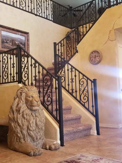 Stone lion statue by staircase with wrought iron railing.