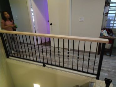 Custom interior steel balcony railing with twisted pickets and wood cap rail.