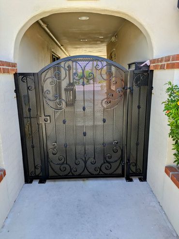 Front entry portico gate with arch top, decorative scrollwork, and perforated mesh.