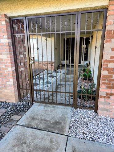 Front entry portico gate with decorative scrollwork, vertical pickets, and ornamental accents.
