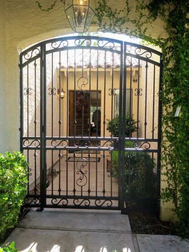 Front entry portico gate with arch top and decorative scrollwork.