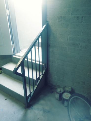 Steel stair railing with vertical pickets for a residential entry stair.