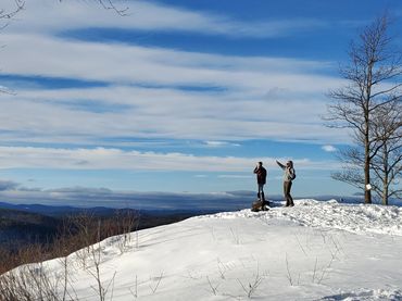 A couple looks out from the snow covered summit at The Pinnacle in Putney Vermont