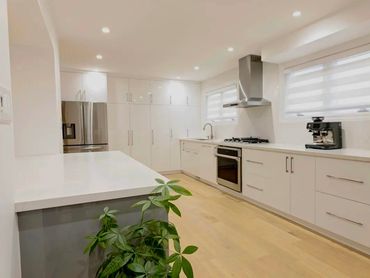 Bright kitchen remodel with wood beam ceiling, white cabinetry, and large waterfall island