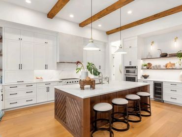 Warm kitchen remodel with island, pendant light, and open layout connected to adjacent living space