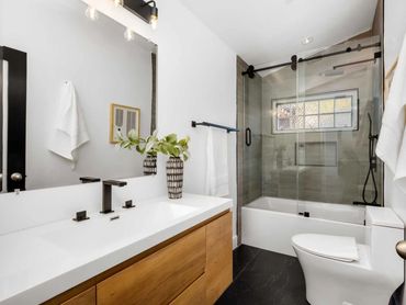 Bathroom remodel with dark wood vanity, glass shower enclosure, and warm layered lighting