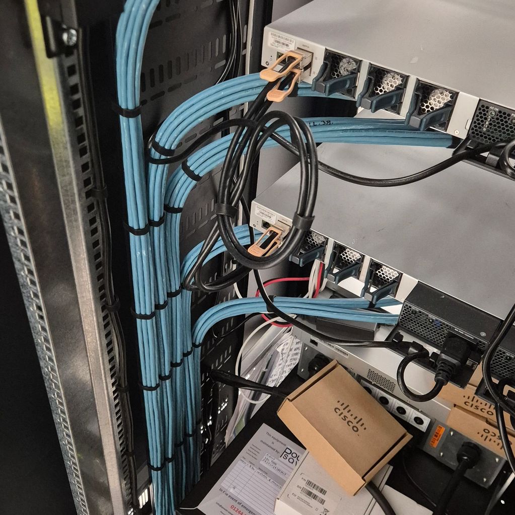 Neatly organized server rack with blue Ethernet cables and Cisco equipment.