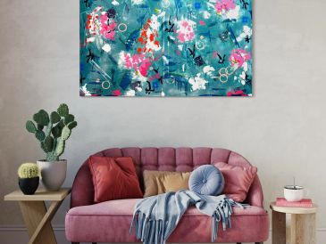 A cozy pink sofa with cushions and a blue throw in a stylish living room.
