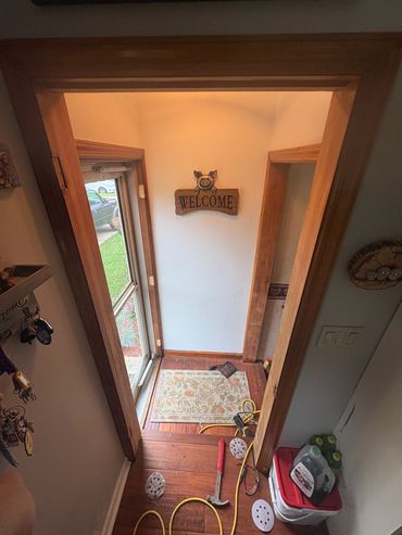 Entryway with a welcome sign, tools, and cleaning supplies scattered on the floor.