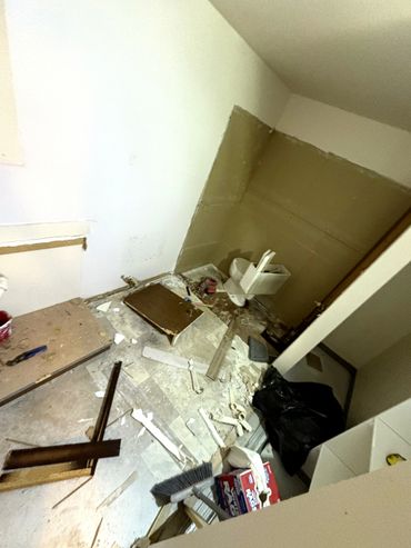 A bathroom under renovation with debris and tools scattered on the floor.