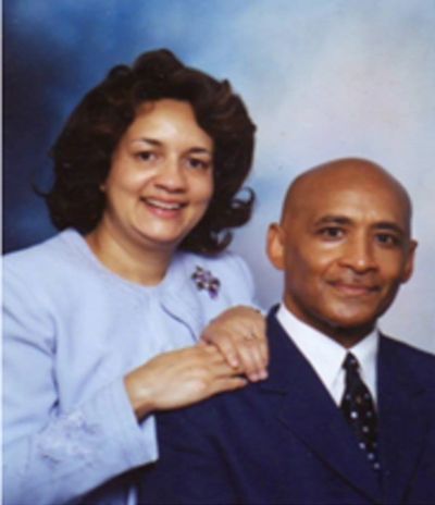 A smiling couple posing for a formal portrait against a blue background.