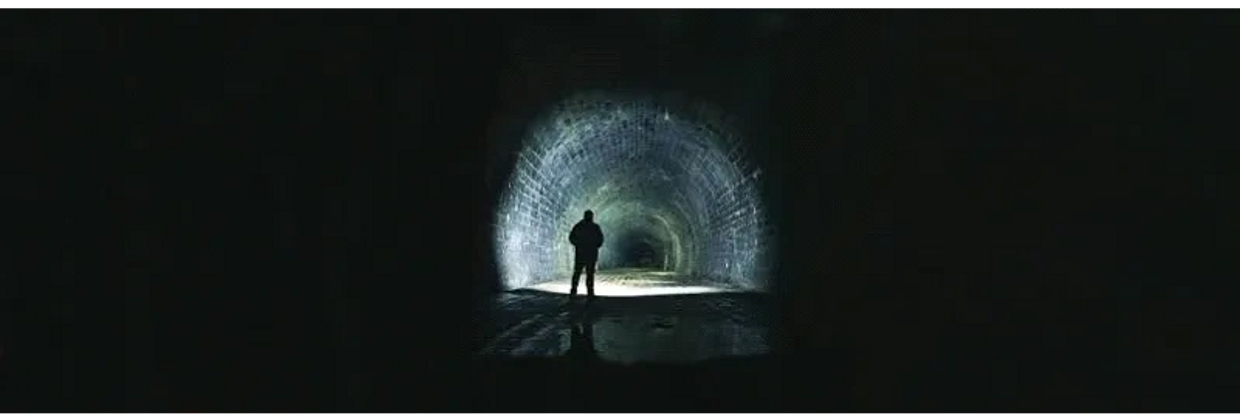 Hidden History Tours UK - dark underground historical tunnel, torchlit with shadows 