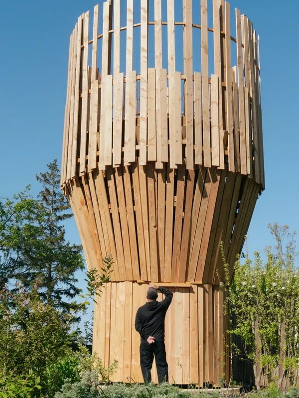 Structure en bois imposante avec un homme l'observant.