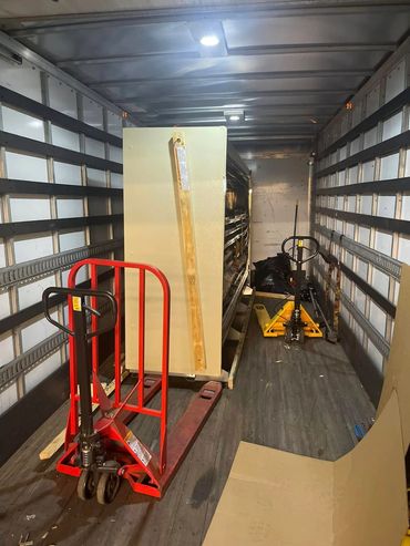 Inside a truck with pallet jacks and a large secured item.