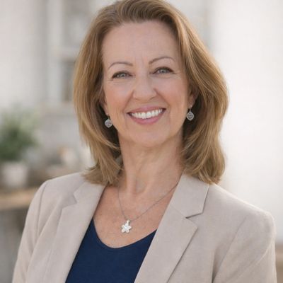 Confident middle-aged woman smiling warmly in professional attire.