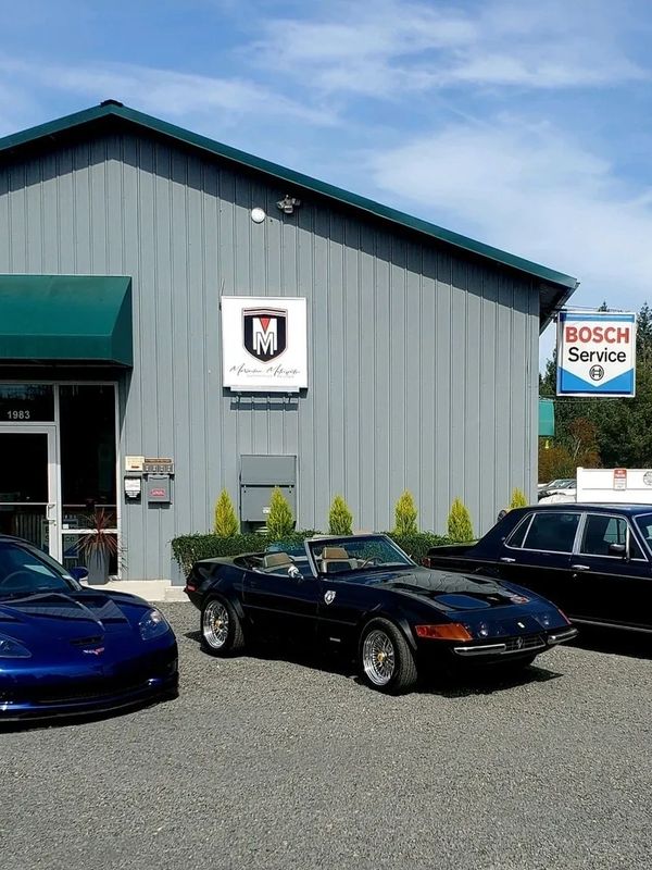 Picture of Maximilian Motorsports storefront. Two corvettes and a Bentley are parked in front.