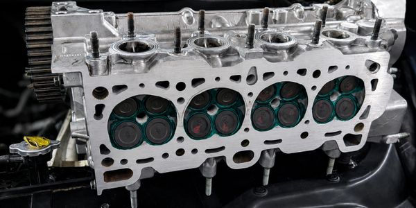 Close-up of a disassembled engine cylinder head with visible valves and ports.