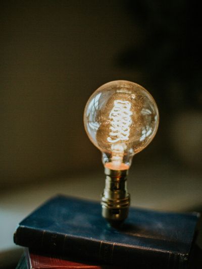 A glowing vintage light bulb atop stacked old books.
