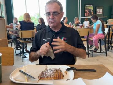 Mayor Dutrey eating pastry on opening day at Montclair's Panera.