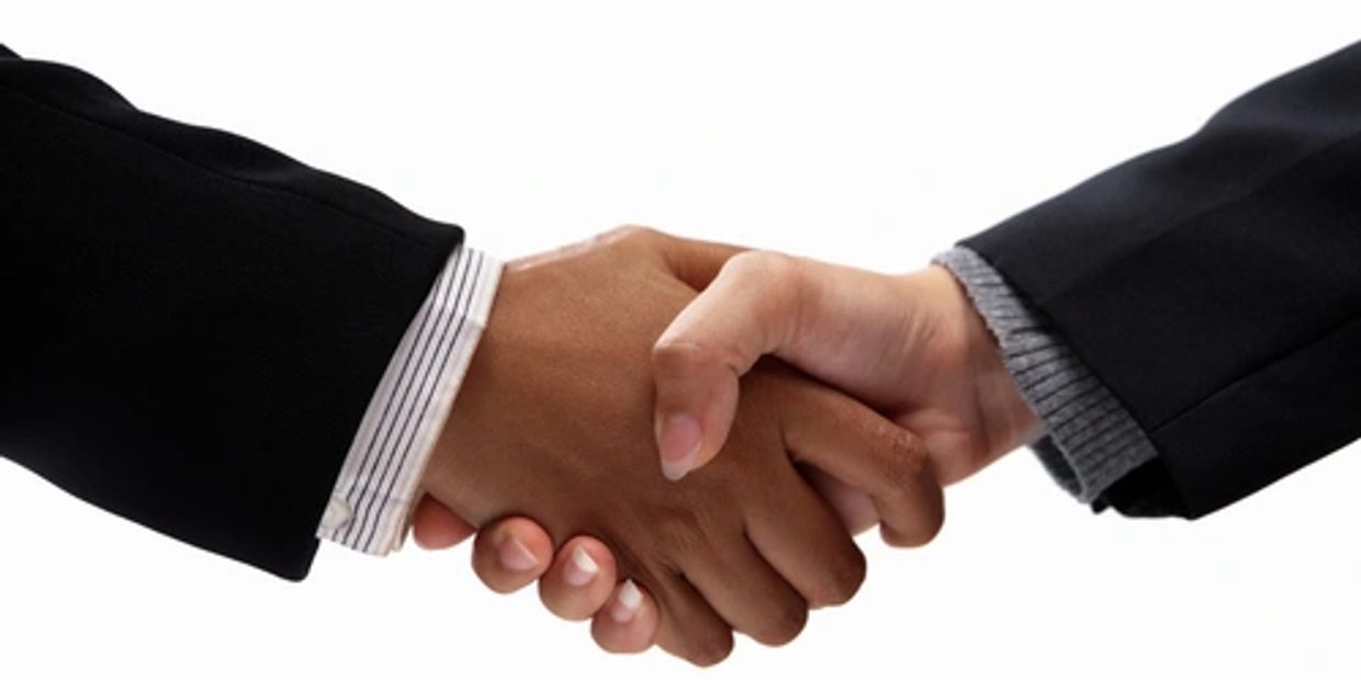 Two people shaking hands in business attire.