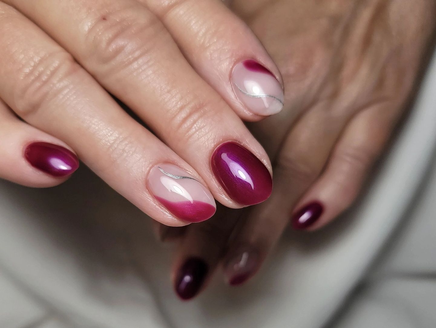 Elegant burgundy and nude nails with silver accent lines.