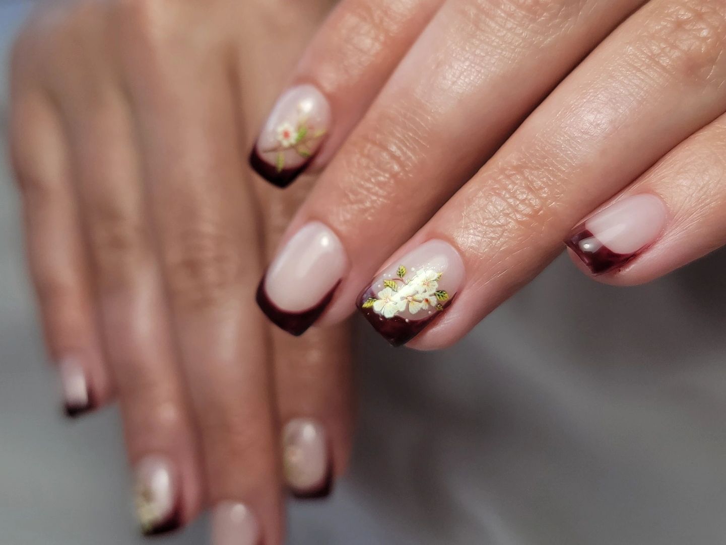 Elegant nails with dark French tips and delicate floral designs.