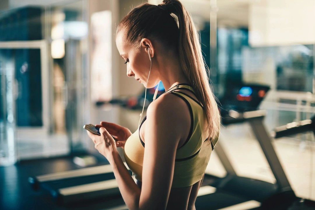 A female in gym is talking with online fitness trainer on mobile phone.