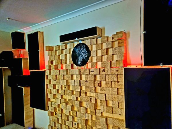 Wooden acoustic panels with speakers and red backlighting on a studio wall.
