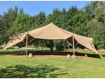 Large beige tent set up in a green grassy area.