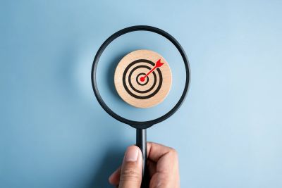 Magnifying glass focusing on a target with a red arrow.