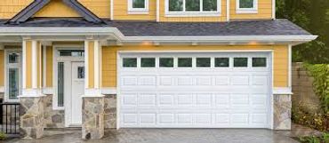 Modern yellow house with white garage door and stone pillars.