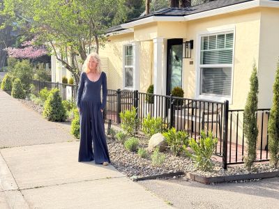 Woman in a blue dress walking outside near a yellow house.