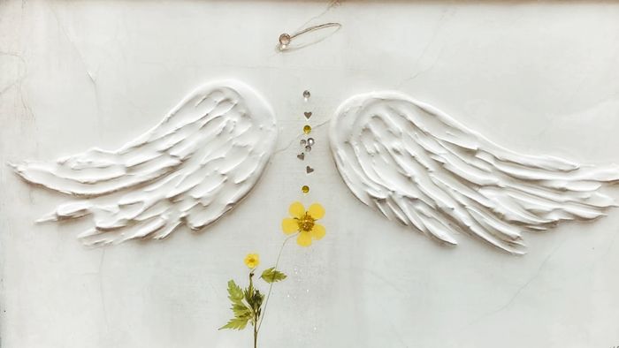 Hand sculpted angel wings on metal. Washed in hues of white. Embellished in dried flowers & hearts.