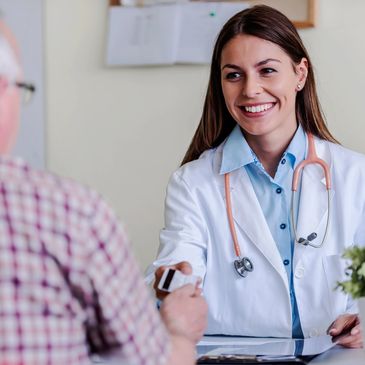 Smiling female doctor handing medicine to an elderly male patient.