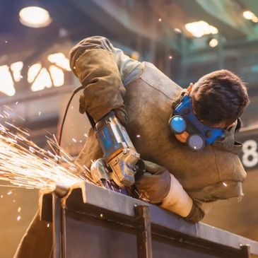 Worker using a grinder with sparks flying in an industrial setting.