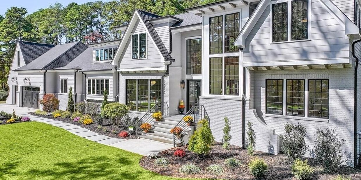 Modern white house with large windows and well-maintained garden.