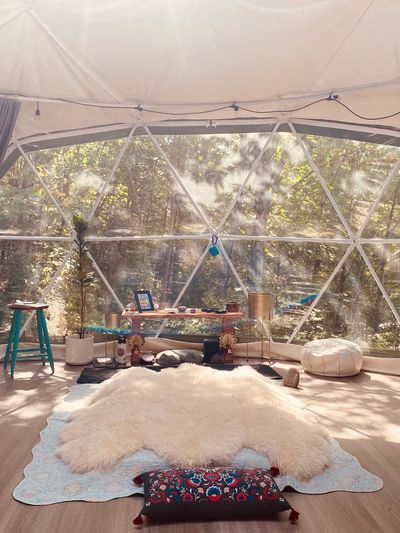 Cozy glamping dome interior with soft rugs and natural sunlight.