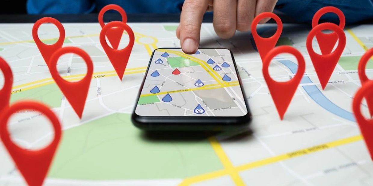 Person using a smartphone with map pins on a map.