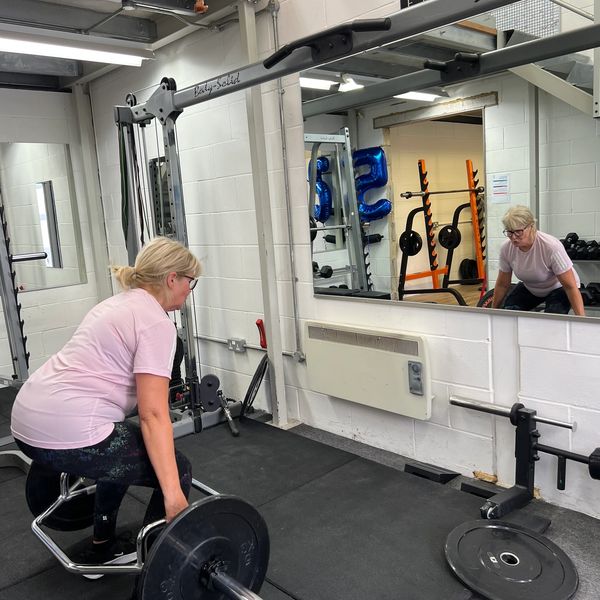 Woman lifting weights with a barbell in a gym, focused and determined.