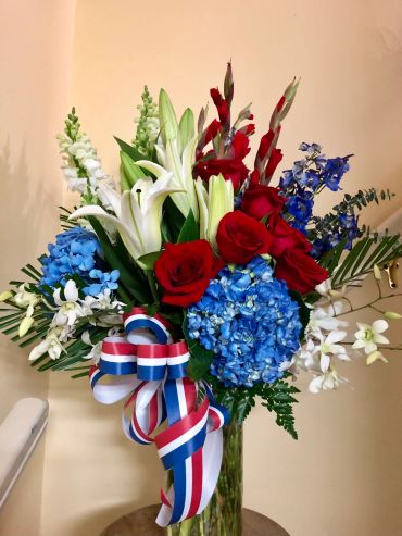 Red, white, and blue floral arrangement with patriotic ribbon.