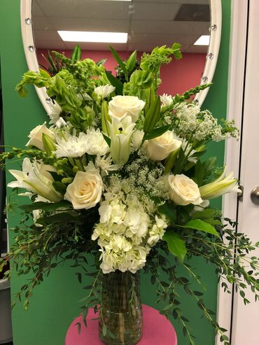Elegant bouquet of white roses and lilies in a vase.