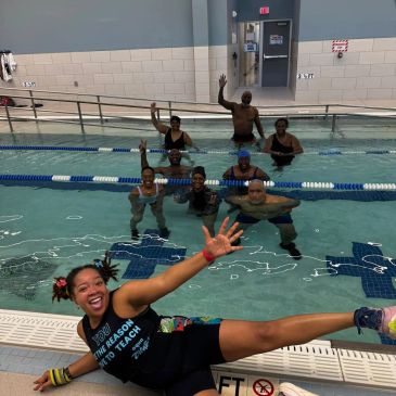 Group of people enjoying in a swimming pool waving.