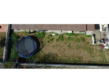 A backyard with a trampoline and sparse grass, viewed from above.