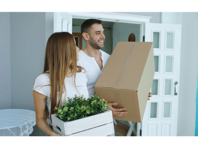 Happy couple carrying boxes while moving into a new home.