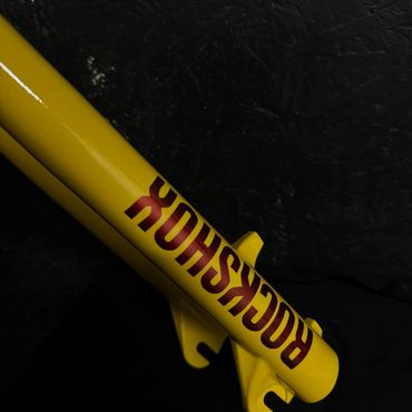 Yellow metal tube with 'ROCKSHOX' text in red on black background.