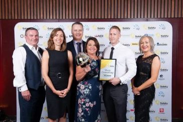 Group of six people posing with an award and certificate at a safety event.